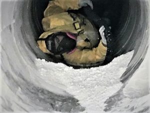 Technician wearing PPE vacuuming duct