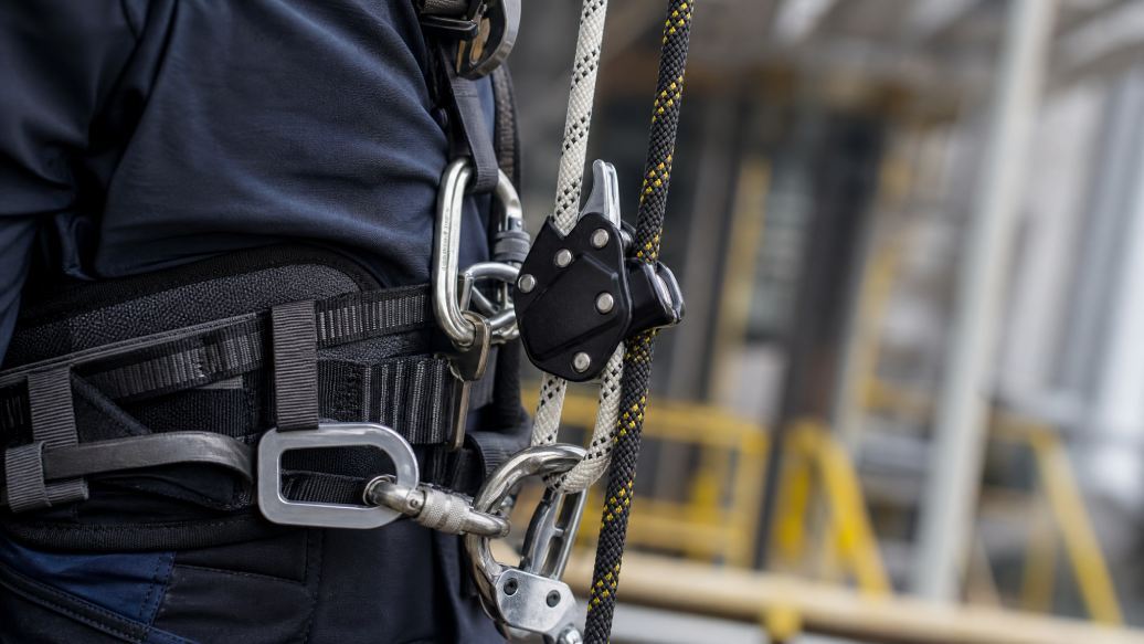 Close-up of rope access safety equipment showing the two-rope system with working line, backup line, and harness attachment points