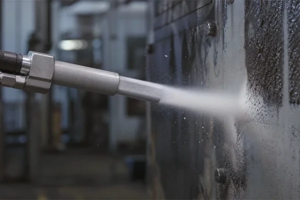 Dry ice blasting nozzle stripping residue from an industrial surface