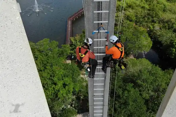 Rope access technician descending an industrial structure on a two-rope system