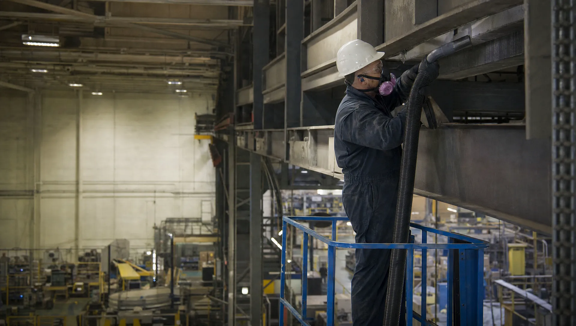 Service-Tech technician removing combustible dust from overhead structures in a Dayton Ohio manufacturing plant