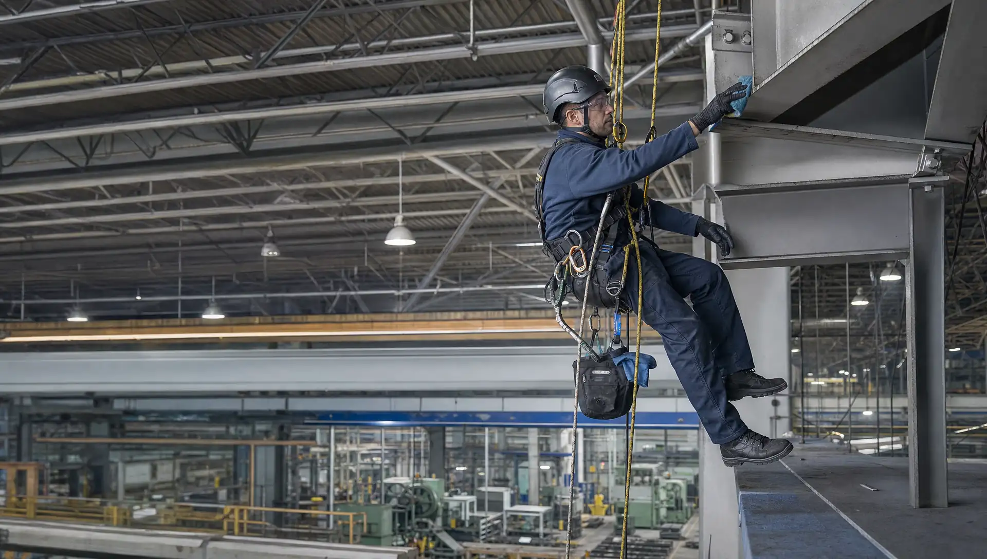 Service-Tech Corporation rope access technician on a redundant two-rope system cleaning overhead structural steel inside a Dayton, Ohio industrial facility