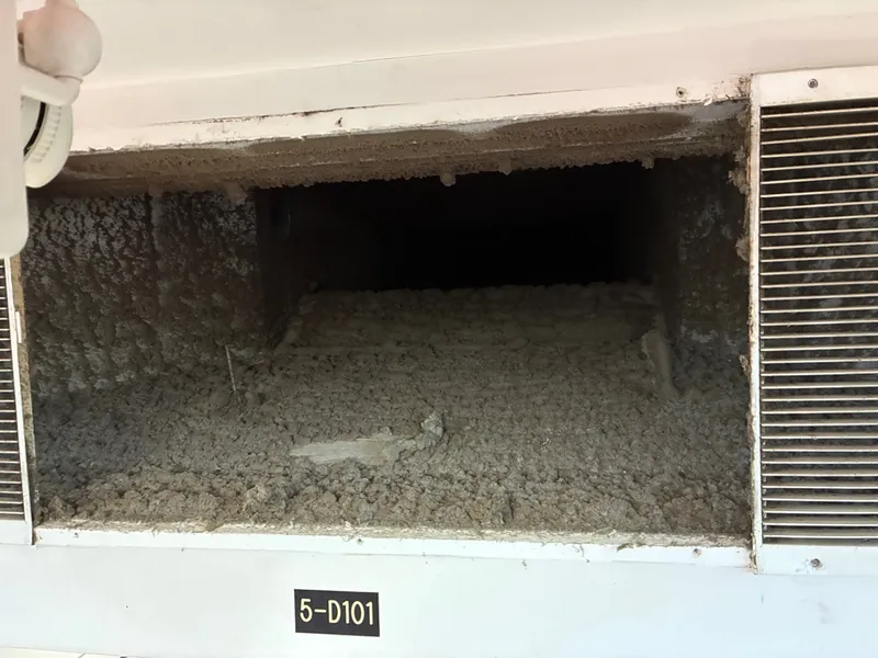 Before: return air plenum with a thick layer of dust and debris on the floor before Service-Tech air duct cleaning