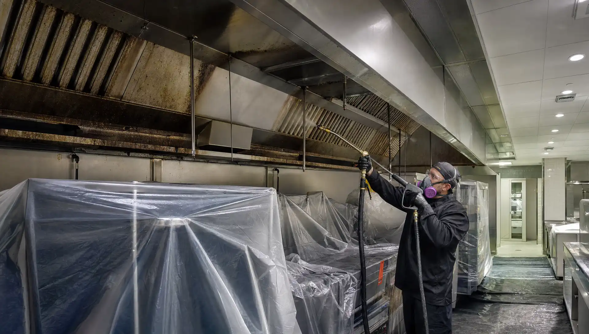 Service-Tech Corporation technician pressure-washing a commercial kitchen exhaust hood to bare metal during an overnight NFPA 96 cleaning at a Tampa, Florida hotel